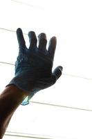 mano de silueta con guantes azules con persianas ligeras. foto