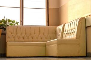 Old cream-colored sofa in the corner of the room with window light. photo