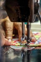 A close up, sewing the fabric on the old machine. photo