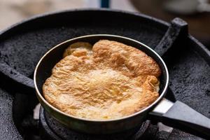 Fried omelette in a small pan on the old gas stove. photo