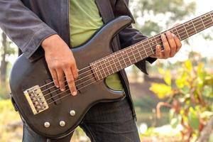 Close to the hands of men playing outdoor bass guitar. photo