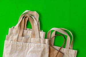 The handle of many cloth bags on the green backdrop. photo