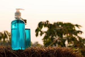 Blue gel bottles and alcohol placed on a straw in the countryside. photo