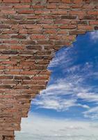 Old brick wall breaking with sky clouds. photo