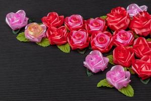 Artificial pink roses on a red background, black, corrugated. photo