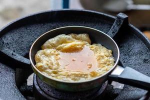 Fried omelette in a small pan on the old gas stove. photo