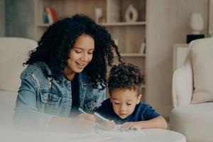 Pretty afro american mom and little boy drawing with colored felt tip pens photo