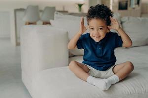 Playful little boy with hands up looking with excited expression at camera photo