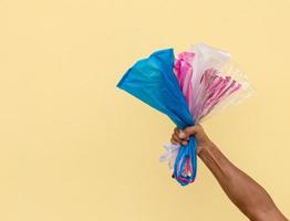 Many plastic bags in the hand against the yellow wall. photo