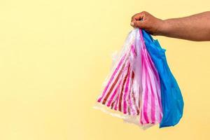 Many plastic bags in the hand against the yellow wall. photo