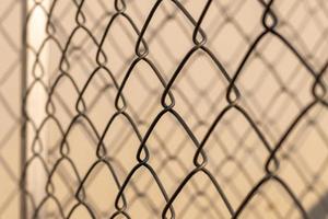 Light, shadow, woven metal grating fence. photo