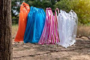 Variety of plastic bags hanging on the barbed wire fence. photo