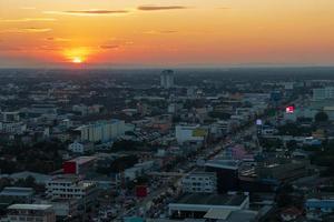 A view from the top of the many buildings that house the traffic of cars on the roads in one of Thailand's provincial capitals during the beautiful sunset at dusk. photo