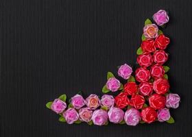 Artificial pink roses on a red background, black, corrugated.