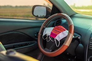 Many face masks are placed on the steering wheel inside the car. photo