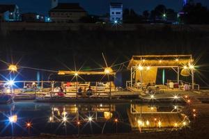 restaurante balsa de bambú flotando en el río con luces por la noche. foto