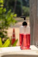 A pink and red gel bottle near the cement wall. photo