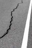 Surface cracks paved rural road near the white line. photo