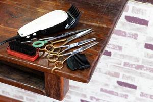 Clippers and many scissors placed on the wooden table. photo