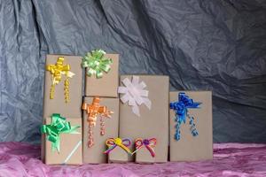 Numerous gift boxes tied with a bow inside a gray canvas. photo