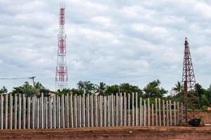 Concrete pillars alongside the river with a crane and telecommunications poles. photo