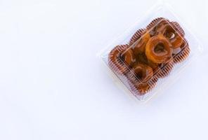 rosquillas fritas de tailandia, recubiertas de caramelo en una caja de plástico transparente sobre un fondo blanco. foto