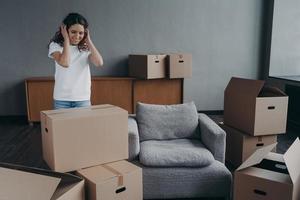 Happy young spanish woman relocates alone. Girl is packing cardboard boxes. Mortgage concept. photo