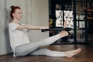 joven y atractiva mujer pelirroja usando el círculo mágico de pilates foto