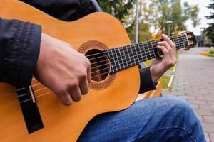 Musician playing a six string guitar in the park photo