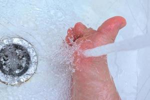 Washing feet with warm running water in the bath to prevent foot fungus photo