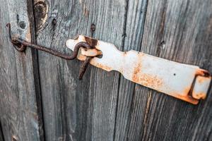 Old and rusty hook locks the old dried up wooden barn door photo