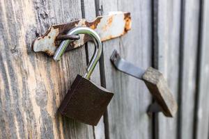 An open padlock hanging from the doors of an old wooden barn photo