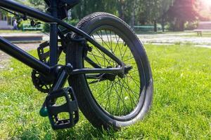 A bicycle and its rear wheel are standing on a green lawn on a bright and sunny, spring day photo