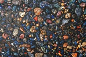 Dark texture of asphalt mixed with many small multi-colored stones photo