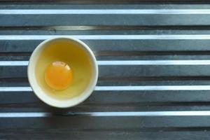 Raw chicken eggs in a cup on the floor of the sink photo