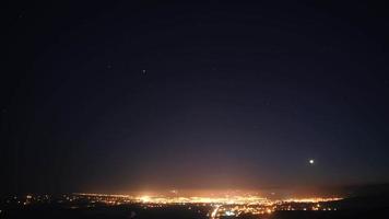 Luces de la ciudad de 8k bajo el cielo estrellado en la noche. video