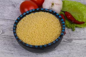 Raw couscous in the bowl served salad leaves, tomato and pepper photo