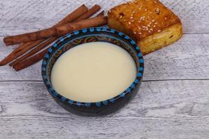 Condenced milk in the bowl with sinnamon and pastry photo