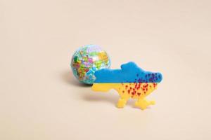 Plasticine yellow and blue map of Ukraine with blood shots and the planet Earth behind. Ukraine defender of the planet concept photo