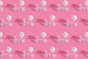 patrón con bicicletas decorativas con flores sobre fondo rosa foto