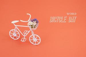 bicicleta decorativa con flores y texto día mundial de la bicicleta sobre fondo naranja foto