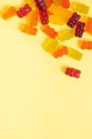 Colored jelly bears on an yellow background with copy space. Top view photo