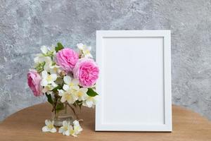 maqueta de marco blanco vacío con flores sobre fondo gris. plantilla para su texto o imagen