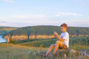 Boy with a phone on a background of beautiful nature photo