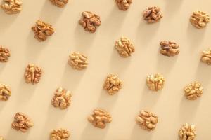 Pattern with peeled halves of walnuts top view. Food abstract background with nuts photo