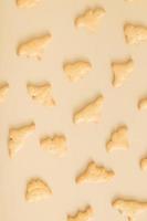 Cookies pattern in the form of dinosaurs top view on a beige background. Monochrome photo