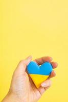 Yellow and blue heart in the colors of the flag of Ukraine in the hand of a woman vertical photo