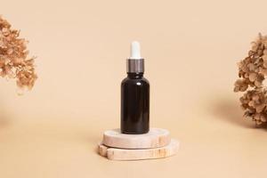 Wooden podium or pedestal with a dropper bottle of cosmetics oil or serum. Neutral beige monochrome skin care concept photo