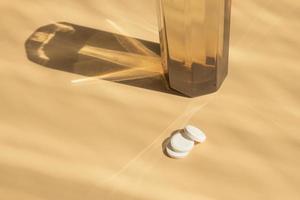 Glass of water and pills on the table with shadows photo