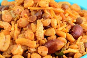 Indian Snacks Mixture roasted nuts with salt pepper masala, pulses, channa masala dal green peas in blue bowl in photo